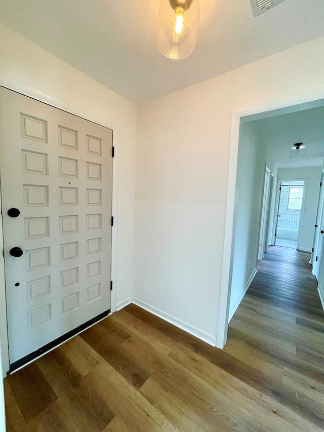 foyer with dark wood-type flooring and baseboards