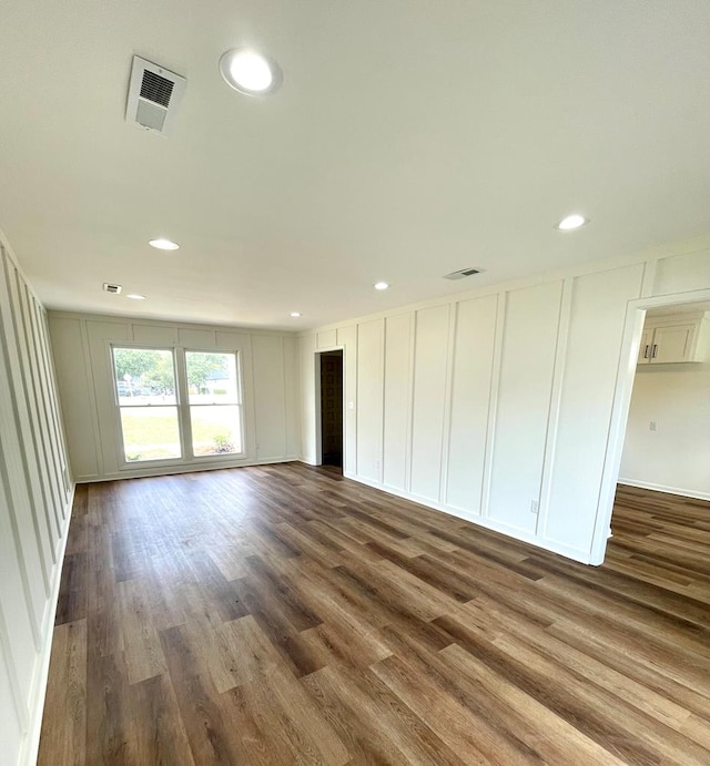 unfurnished room with recessed lighting, dark wood-style flooring, visible vents, and a decorative wall