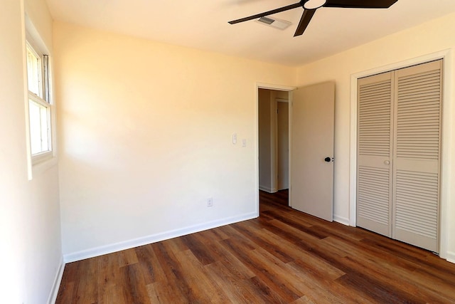 unfurnished bedroom featuring baseboards, a closet, visible vents, and dark wood-style flooring