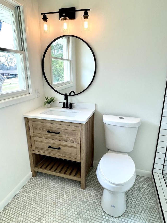 bathroom with toilet, baseboards, and vanity