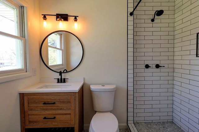 full bathroom featuring a tile shower, vanity, and toilet