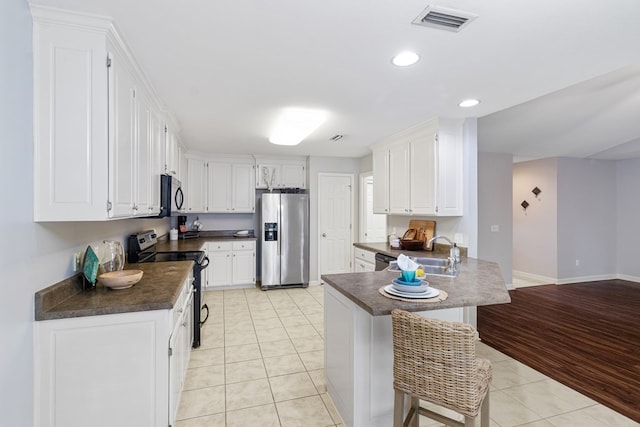kitchen featuring stainless steel fridge with ice dispenser, a sink, range with electric cooktop, dark countertops, and a peninsula