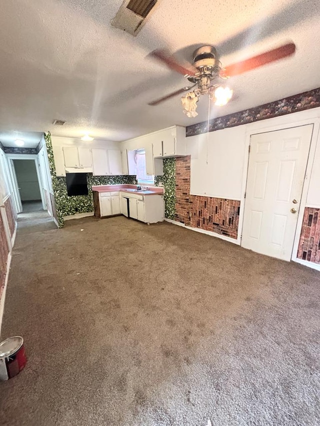 kitchen with sink, white cabinetry, a textured ceiling, dark carpet, and ceiling fan