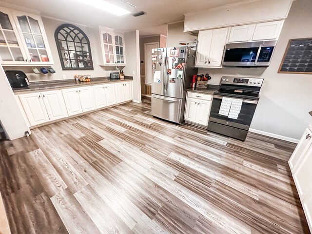 178 W Lawrence Harris Hwy, Slocomb, AL 36375 - kitchen with stainless steel appliances, white cabinets, glass insert cabinets, and light wood-style floors