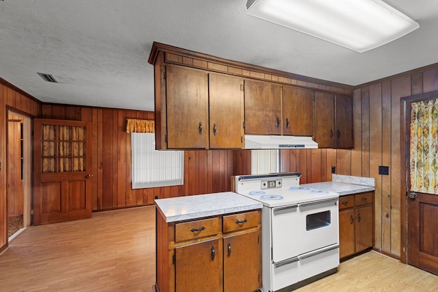 kitchen featuring a textured ceiling, light hardwood / wood-style floors, white electric stove, and wood walls