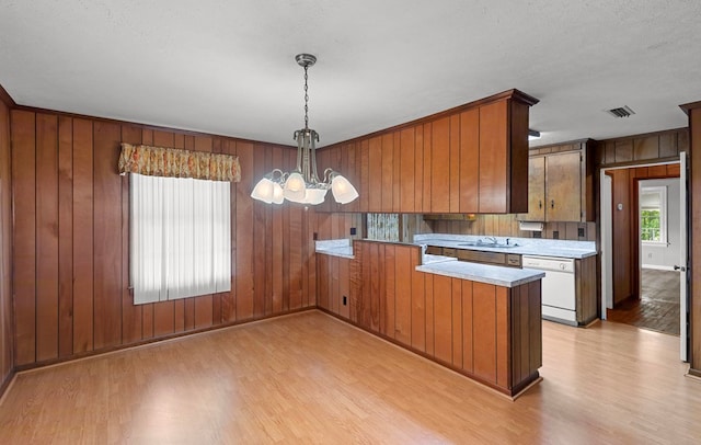 kitchen featuring pendant lighting, white dishwasher, sink, light wood-type flooring, and a chandelier