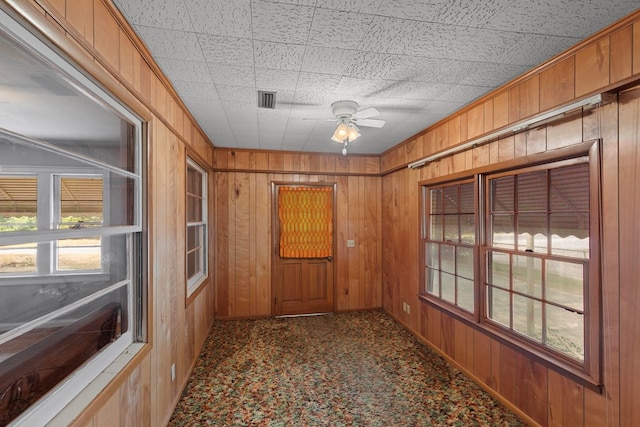 hallway featuring wooden walls and carpet floors