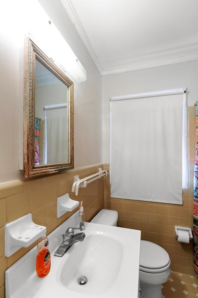 bathroom with crown molding, sink, tile walls, and toilet