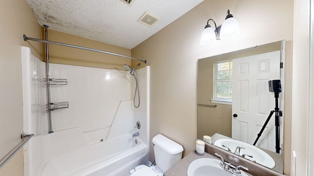 full bathroom featuring washtub / shower combination, a textured ceiling, toilet, and sink