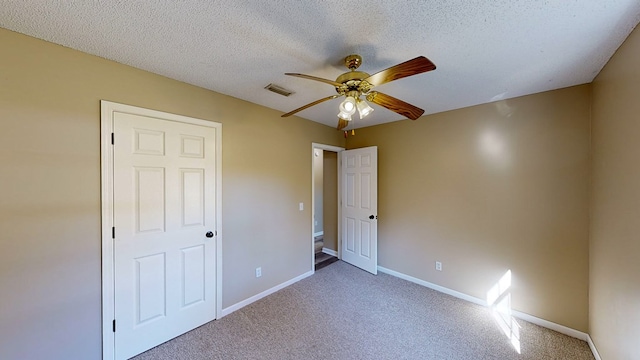 unfurnished bedroom featuring ceiling fan, carpet floors, and a textured ceiling