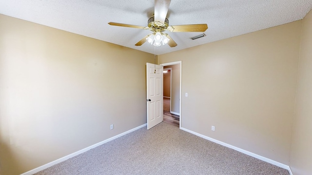 empty room featuring ceiling fan, light colored carpet, and a textured ceiling