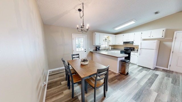 dining room featuring a textured ceiling, vaulted ceiling, sink, light hardwood / wood-style flooring, and a notable chandelier