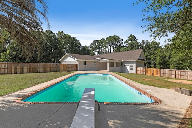 view of swimming pool featuring a yard and a diving board