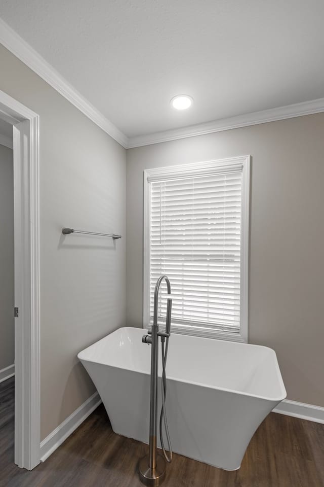 bathroom featuring a bath, hardwood / wood-style flooring, crown molding, and sink