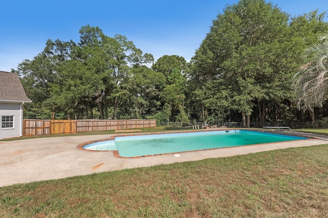 view of swimming pool featuring a lawn, a diving board, and a patio