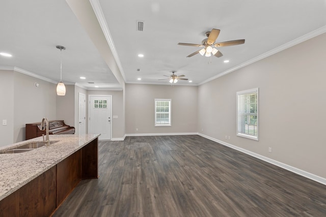 kitchen featuring pendant lighting, sink, dark hardwood / wood-style floors, ornamental molding, and light stone counters