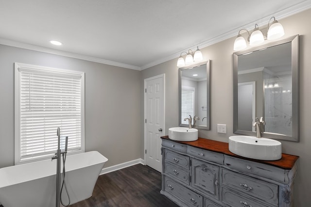 bathroom featuring a tub to relax in, crown molding, vanity, and wood-type flooring