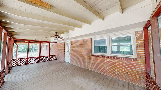 unfurnished sunroom featuring beamed ceiling and ceiling fan