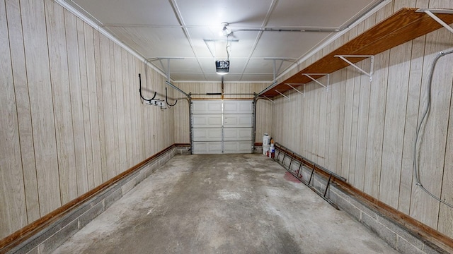 garage with a garage door opener and wood walls