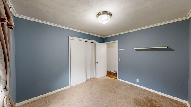 unfurnished bedroom featuring a closet, light colored carpet, a textured ceiling, and ornamental molding