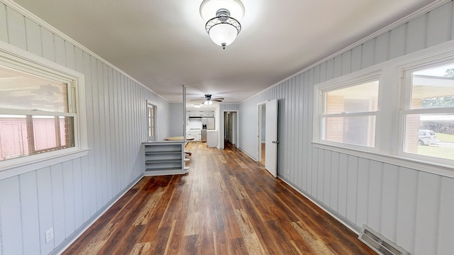 hallway with crown molding, dark wood-type flooring, and wood walls