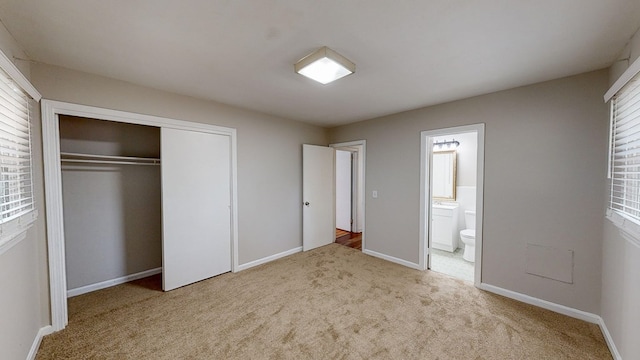 unfurnished bedroom with light carpet, ensuite bath, and a closet