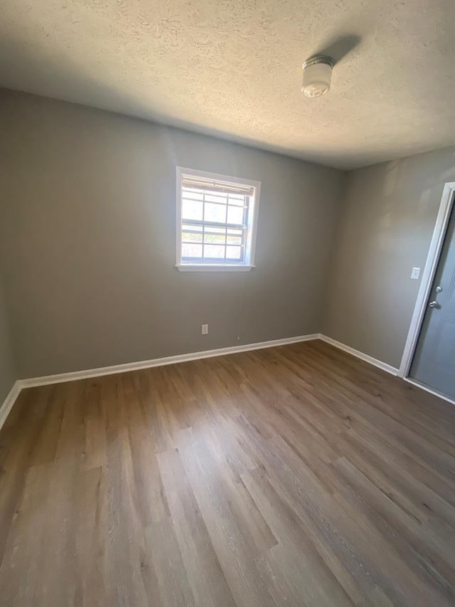 spare room featuring wood-type flooring and a textured ceiling