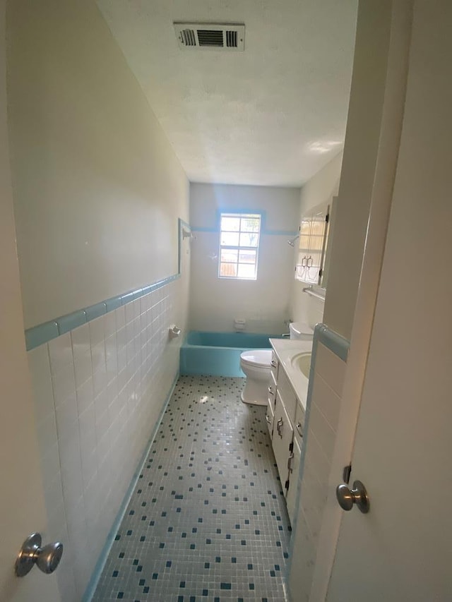 full bathroom featuring shower / tub combination, vanity, toilet, and tile walls