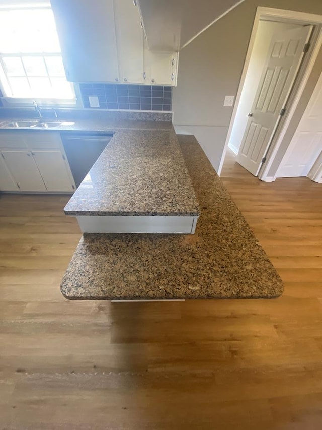 details featuring stone counters, sink, decorative backsplash, light wood-type flooring, and white cabinetry