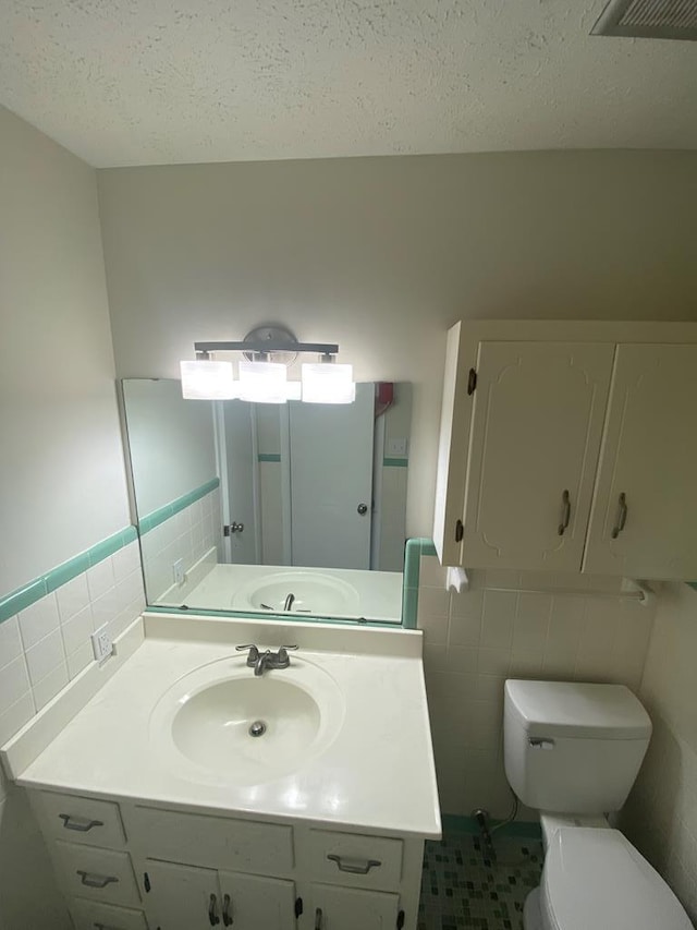 bathroom with tile patterned floors, vanity, toilet, and tile walls