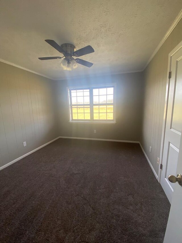 spare room with ceiling fan, crown molding, a textured ceiling, and dark colored carpet