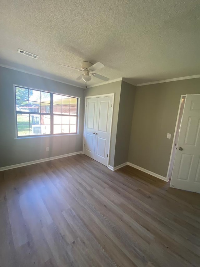 unfurnished bedroom with a textured ceiling, ceiling fan, crown molding, hardwood / wood-style flooring, and a closet