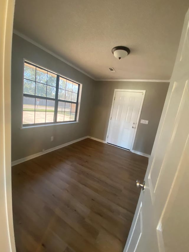 interior space featuring a textured ceiling, dark hardwood / wood-style floors, and ornamental molding