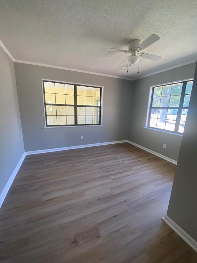 empty room with a textured ceiling, ceiling fan, ornamental molding, and dark wood-type flooring