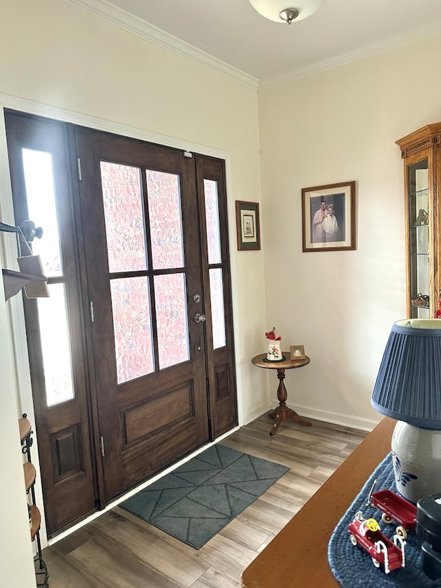 entryway with wood finished floors, crown molding, and baseboards