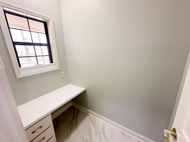 office space featuring baseboards, marble finish floor, and built in study area