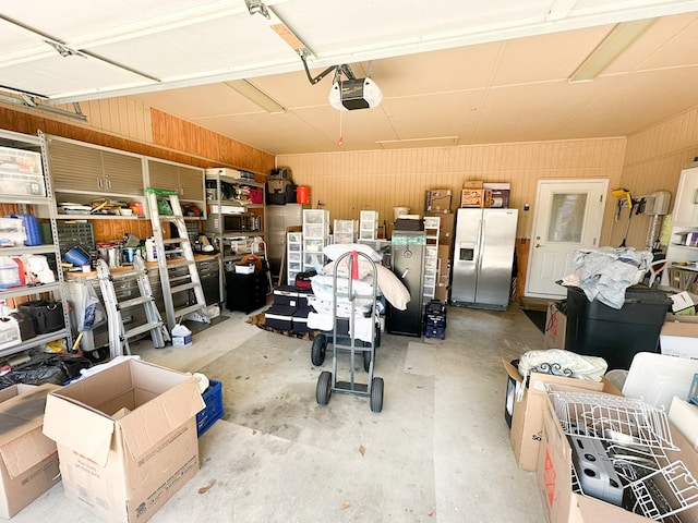 garage with a garage door opener and stainless steel fridge with ice dispenser