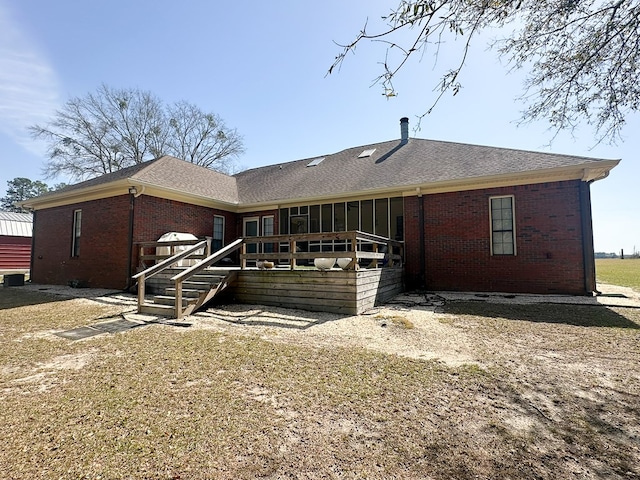 back of property featuring brick siding, a shingled roof, and a deck