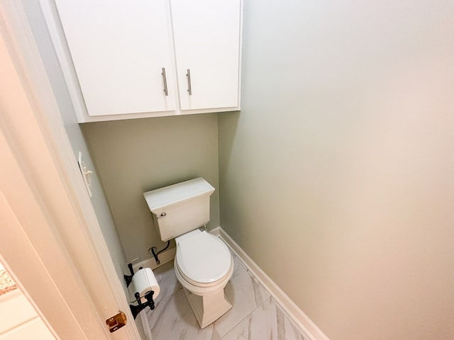 bathroom featuring toilet, baseboards, and marble finish floor