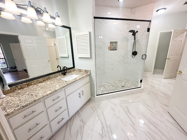 bathroom featuring vanity, baseboards, marble finish floor, and a stall shower