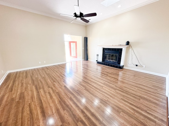 unfurnished living room featuring a fireplace, light wood-type flooring, crown molding, and baseboards