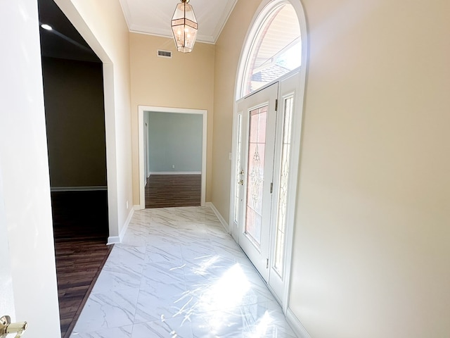 foyer entrance with visible vents, marble finish floor, ornamental molding, baseboards, and a towering ceiling