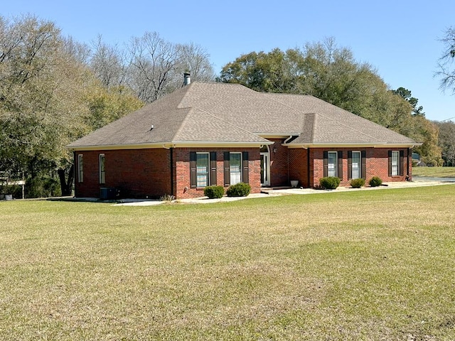 view of front of property with a front lawn, brick siding, and roof with shingles