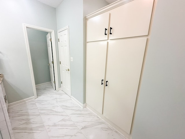 corridor with marble finish floor and baseboards