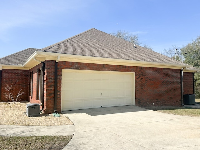 view of side of property with a garage, brick siding, driveway, and a shingled roof