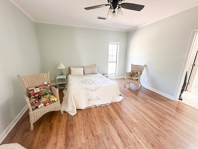 bedroom with baseboards, light wood-style floors, visible vents, and ornamental molding