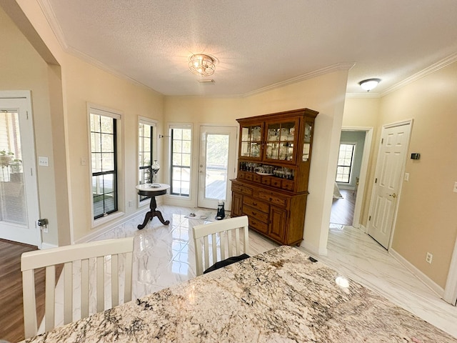 interior space featuring marble finish floor, a textured ceiling, crown molding, and baseboards