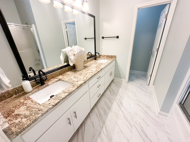 full bathroom with double vanity, marble finish floor, a shower with door, and a sink