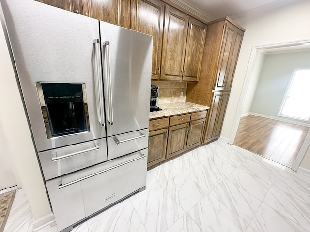 kitchen with stainless steel fridge with ice dispenser, ornamental molding, light stone counters, brown cabinets, and marble finish floor