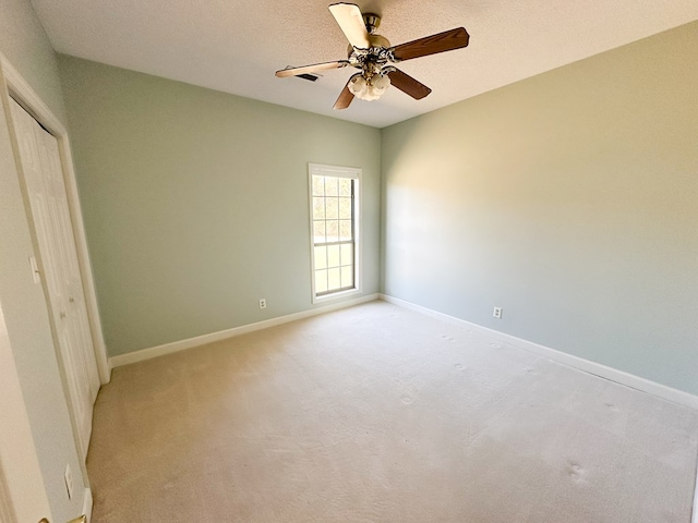 unfurnished bedroom with baseboards, ceiling fan, light colored carpet, a closet, and a textured ceiling